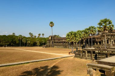 Angkor Vat 'ın onur terası, açık mavi gökyüzünün altında yüksek palmiye ağaçları ve sık ormanlarla çevrili kuru çimenler ve kumlu yollar boyunca uzanır. Yıpranmış kumtaşı mimarisi ve açık zemin bu tarihsel simetrinin anıtsallığını ve simetrisini anımsatıyor