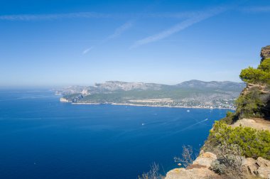 Yüksek görüş açısı, derin mavi Akdeniz sularına tepeden bakan Cap Canaille 'nin dramatik uçurumlarını gözler önüne seriyor. Çam bitkisi ve parlak bir gökyüzünün altında engebeli kayalar. Cassis ve uzak Calanques kıyı şeridi ufuk boyunca uzanır