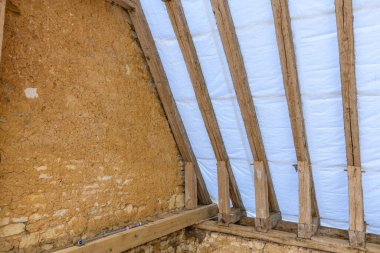 Korunmasız kirişler, kaba toprak duvarının üzerinde şeffaf bir koruyucu muşambayı destekler ve geleneksel kırsal yapının ham dokularını ve malzemelerini ortaya çıkarır. Yumuşak gün ışığı geometrik yapıyı vurgular ve yıpranmış odunları