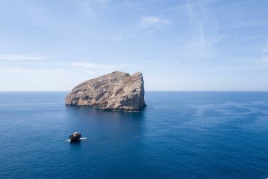 Sardinya, Porto Conte yakınlarındaki Akdeniz 'in sakin mavi sularından büyük, engebeli bir kayalık ada yükseliyor. Sahne, bulutlarla kaplı engin bir gökyüzünün altında yumuşak bir gün ışığıyla yıkanır..