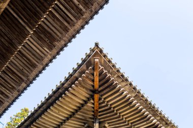 Japonya 'nın Himeji kentindeki Engyoji Dağı' nda soluk mavi gökyüzünün altında buluşan iki geleneksel ahşap tapınağın simetrik görüntüsü. Karmaşık işçilik ve doğal ahşap dokular parlak gün ışığıyla vurgulanır..