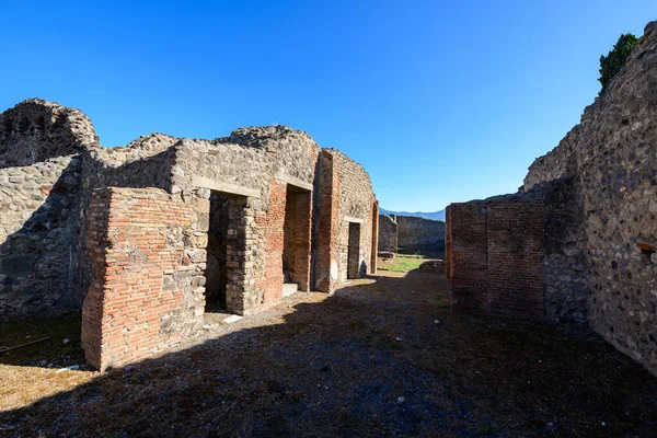 Antik tuğla ve taş duvarlar İtalya 'nın Pompeii kentindeki Cornelli Hanedanı' nın kalıntılarını oluşturur. Parlak güneş ışığı ve derin gölgeler, canlı mavi Akdeniz gökyüzünün altındaki dokulu duvarları vurgular..