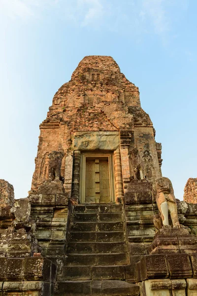 Altın güneş ışığı, yıpranmış tuğla kuleyi ve Kamboçya 'daki Pre Rup tapınağının karmaşık bir şekilde oyulmuş kapısını aydınlatıyor. Sahnede dik taş basamaklar, koruyucu aslan heykelleri ve temiz bir gökyüzüne karşı dokulu masonluk yer alıyor.