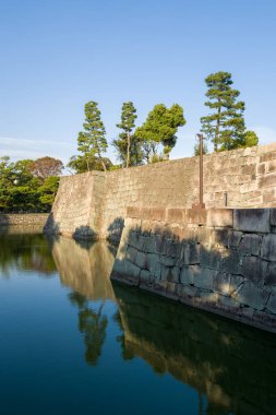 Japonya 'nın Kyoto kentindeki Nijo Kalesi' nin durgun sularına yansıyan uzun yeşil ağaçlarla, sakin bir hendeğin üzerinde, sıcak güneş ışığıyla yıkanan devasa taş duvarlar yükseliyor..