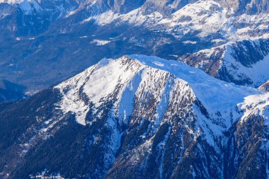 Aiguillette des Houches 'ın yüksek açılı manzarası, karla kaplı geniş bir yayla çevrili dik orman yamaçları ve derin vadilerle çevrili, kışın kışın güneşiyle aydınlanmış..
