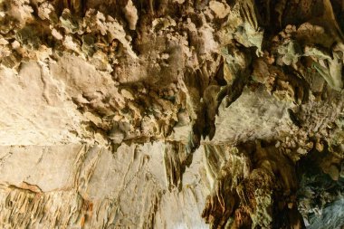 Detaylı mineral oluşumları ve katmanlı kaya dokuları merkez Laos 'taki Konglor Mağarası' nın tavanını kaplıyor. Engebeli yüzey su akışı ve mineral yatakları tarafından şekillenen doğal desenleri ortaya koyuyor..