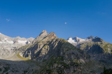Pürüzlü granit dağlar ve parlak mavi gökyüzüne karşı yükselen buzullar engebeli dokular ve dramatik gölgeler Mont Blanc kalabalığında çarpıcı bir alp manzarası yaratıyor..