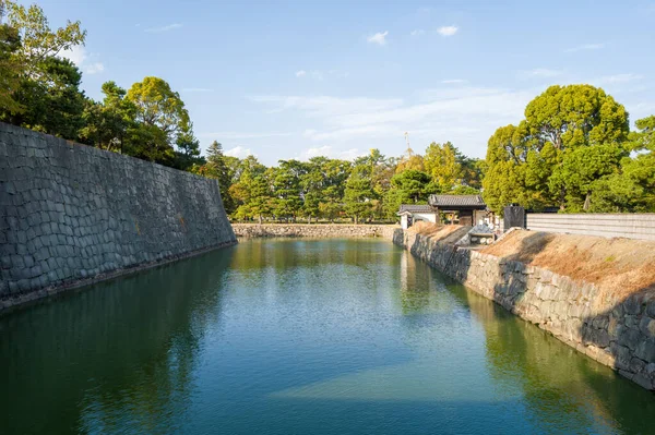 Japonya 'nın Kyoto kentindeki Nijo Kalesi' nde mavi gökyüzü altında geleneksel kapı mimarisine sahip heybetli taş duvarlar ve yemyeşil ağaçlarla çevrili geniş hendek..