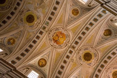 Bosa, Sardinya 'daki Cattedrale dellImmacolata Concezione' nin içinde ayrıntılı freskler ve geometrik desenlerle donatılmış karmaşık bir tavan. Sıcak doğal ışık, özenle hazırlanmış sıva ve klasik motifleri vurgular.