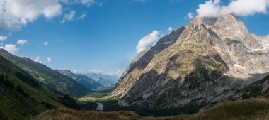 Bereketli Val Ferret Vadisi 'nin geniş manzarası engebeli dağlar ve dağılmış bulutlar tarafından çevrelenmiş parlak mavi bir gökyüzü altında..