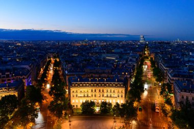 Paris 'teki Wagram Bulvarı' nın gece görüşü aydınlanmış Haussmann binaları, ağaçlarla kaplı sokaklar ve parlak şehir ışıkları derin mavi bir gökyüzünün altında ufka doğru uzanıyor..