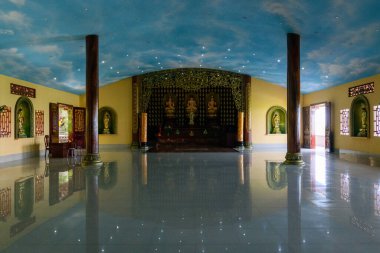 Geniş bir tapınağın içinde parlak yansıtıcı zemin, altın aksanlı uzun ahşap sütunlar ve altın heykellerle süslenmiş canlı bir sunak var. Tavan gerçekçi bir gökyüzü duvar resmiyle boyanmış. Havalı ve canlandırıcı bir atmosfer yaratıyor..