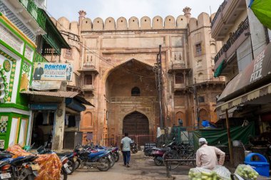 Prayagraj, Hindistan - 21 Mart 2024: Görüntü Khusro Bagh 'ın güney girişini gösteriyor, dükkanlar, park edilmiş motosikletler, elektrik kabloları ve gündüz vakti insanlarla çevrili geniş bir Babür döneminden kalma kemerli bir kapı..