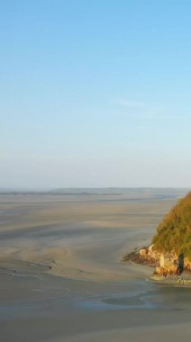 Fransa 'nın Le Mont-Saint-Michel yakınlarındaki açık mavi gökyüzünün altında geniş gelgit kumu düzlükleri sükunet ve açık alan hissi uyandırıyor..