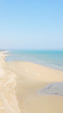 Utah Beach, Normandiya 'da açık mavi bir gökyüzü altında yumuşak dalgalarla geniş kumlu sahil şeridi. Huzurlu kıyı manzarası seyahat ve doğa kavramları için ideal..