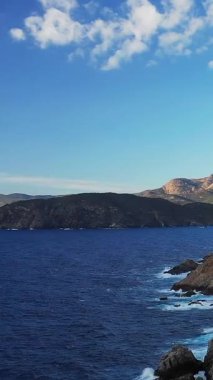 Derin mavi denizi ve parlak bir gökyüzü altında uzak tepeleri olan dramatik kayalık kıyı şeridi, Cargese, Korsika yakınlarında ele geçirildi. Seyahat, doğa ve Akdeniz temaları için ideal.