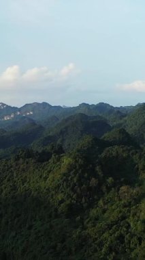 Vietnam 'da, Cao Bang yakınlarında berrak bir gökyüzünün altındaki yoğun yeşil dağların manzarası. Huzurlu doğal manzara Yuvarlanan tepeler ve yumuşak güneş ışığı.