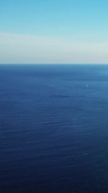 Açık bir gökyüzünün altındaki derin mavi Akdeniz 'in sakin manzarası ufuk çizgisinde Bonifacio, Korsika yakınlarında görünen uzak bir yelkenli..