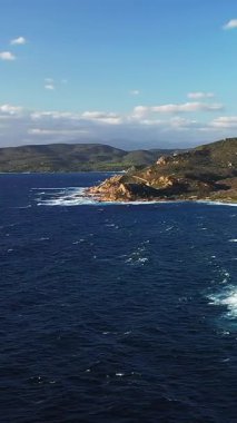 Korsika, Les Iles Sanguinaires 'teki engebeli kıyı şeridi ve derin mavi deniz manzarası, berrak bir gökyüzünün altında. Dramatik uçurumları ve dalgaları olan Akdeniz manzarası.