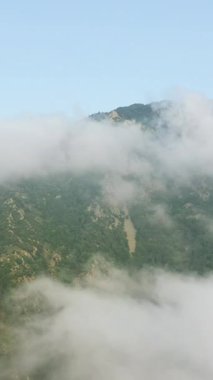 Yeşil yemyeşil dağlar kısmen alçak asılı bulutlar ve Pireneler 'de sis ile kaplı. Berrak mavi gökyüzünün altındaki sakin doğal manzara.