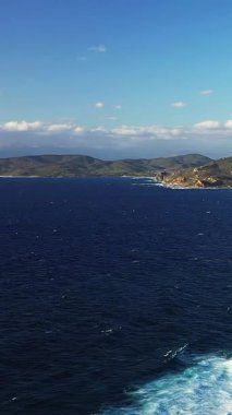 Derin mavi deniz manzarası ve açık bir gökyüzünün altında Korsika 'daki Les Iles Sanguinaires' in engebeli kıyı şeridi. Dalgaların kayalık kıyılara çarptığı doğal manzara.