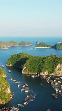 Temiz mavi gökyüzünün altında Cat Ba Bay, Vietnam 'daki yemyeşil kireçtaşı adaları arasında kayıkların ve yüzen yapıların havadan görünüşü.