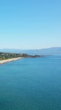 Yunanistan 'ın Gythio kenti yakınlarındaki turkuaz sular, kumlu plajlar ve uzak dağlarla sakin bir kıyı şeridinin manzarası..