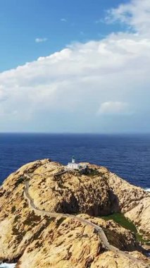 Korsika 'nın Fanale di Petra yakınlarındaki derin mavi Akdeniz' e bakan engebeli uçurumların tepesine tünemiş manzaralı bir deniz feneri. Parlak gökyüzü ve dramatik kıyı şeridi çarpıcı bir manzara yaratır..