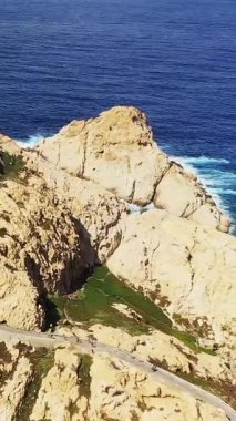 Korsika Fanale di Petra 'daki engebeli kayalık uçurumlar ve derin mavi deniz manzarası. Sarmal yolları ve dalgaları kayalara çarpan dramatik kıyı manzarası.