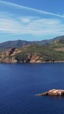 Fransa 'nın Korsika şehrinde engebeli Calanques de Piana kıyı şeridinin derin mavi denizi ve kayalık tepeleri manzarası.