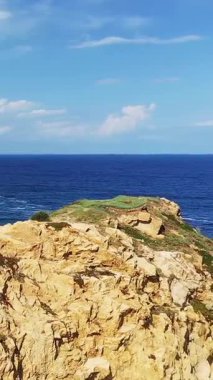 Büyük ihtimalle Fanale di Petra, Sardinya, İtalya yakınlarındaki açık mavi bir gökyüzünün altındaki engebeli kayalık manzarası..