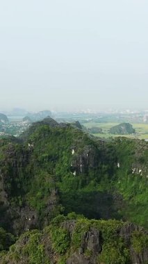 Yeşil kireçtaşı karst dağlarının manzarası ve Vietnam, Ninh Binh 'deki uzak tarlalar, sisli bir gökyüzünün altında..