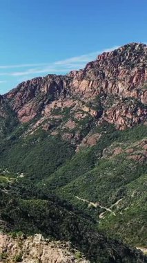 Korsika kırsalındaki kayalık dağların ve yemyeşil vadilerin manzarası güneşli bir günde.