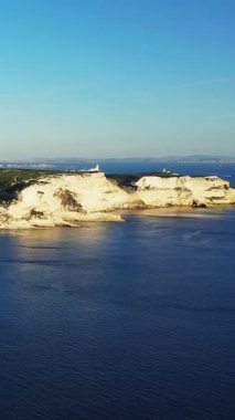 Bonifacio, Korsika kıyı şeridi boyunca derin mavi deniz ve açık gökyüzü ile dramatik beyaz kireçtaşı uçurumları. Engebeli doğal manzara güneş ışığıyla yıkandı..