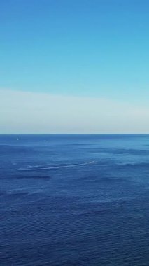 Korsika Bonifacio yakınlarında berrak bir gökyüzünün altında sakin mavi Akdeniz manzarası. Küçük bir tekne suda hafif bir uyanış bırakır..