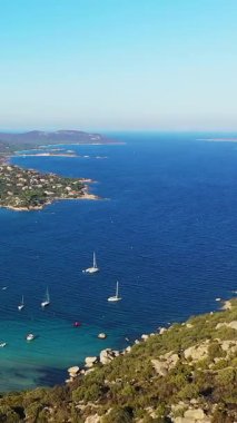 Portekiz 'in Albufeira yakınlarındaki açık mavi kıyı şeridinin hava manzarasında demirli yelkenliler ve yemyeşil tepeler yer alıyor. Idyllic Akdeniz manzarası Parlak bir gökyüzü altında.
