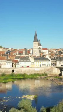 La Charite-sur-Loire manzarası. Geleneksel binalar, kilise kulesi ve açık mavi gökyüzünün altındaki Loire Nehri..
