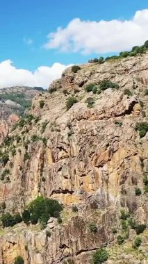 Korsika 'daki Vallee de Porto' da mavi gökyüzünün altında dağınık yeşil bitki örtüsü olan dramatik kayalık uçurumlar. Seyahat ve macera teması için ideal engebeli doğal manzara.