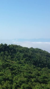 Dien Bien Phu, Vietnam 'da açık mavi bir gökyüzünün altında, üzerinde bulutlardan bir battaniye ile yemyeşil tepeler. Huzurlu doğal manzara seyahat ve doğa kavramları için ideal..