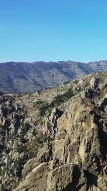 Fransa, Korsika 'daki Col de Bavella' da açık mavi gökyüzü altında dramatik kayalık dağ manzarası. Engebeli arazi ve doğal güzellik macera ve seyahat temaları için idealdir.