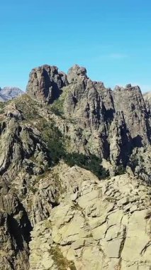 Fransa 'nın Korsika şehrindeki Col de Bavella' da açık mavi gökyüzünün altında dramatik kayalık zirveler. Nadir bitki örtüsü ve çarpıcı jeolojik oluşumları olan engebeli bir arazi..