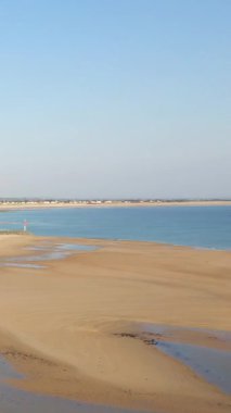 Fransa, Plage de la Potiniere 'de sakin mavi denizi ve berrak gökyüzü olan geniş kumlu bir sahil. Huzurlu kıyı manzarası rahatlama ve seyahat kavramları için ideal.