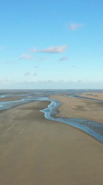 Utah Sahili, Normandiya, Fransa 'da açık mavi gökyüzü altında geniş kumlu gelgit düzlükleri ve sığ su kanallarının havadan görüntüsü.