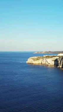Bonifacio, Korsika 'da açık bir gökyüzünün altında, derin mavi Akdeniz' in üzerinde dramatik beyaz kireçtaşı kayalıkları yükseliyor. Manzaralı kıyı şeridi huzurlu ve resimli bir manzara sunuyor..