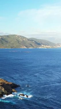 Derin mavi deniz manzarası kayalık kıyı şeridi ve uzak yeşil tepeler, Les Iles Sanguinaires, Korsika 'da yakalandı..