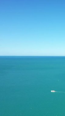 İtalya 'daki Isola Varano Doğa Rezervi' nde berrak mavi bir gökyüzü altında durgun turkuaz sularda küçük bir tekne seyahat ediyor..