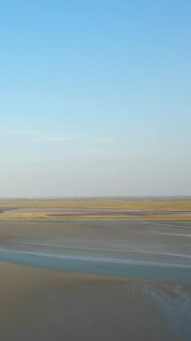 Fransa 'nın Le Mont-Saint-Michel körfezindeki açık mavi gökyüzünün altında gelgit düzlükleri ve sığ su kanalları geniş bir görüş alanıdır..