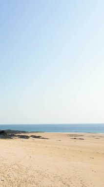 Dağılmış kayaları olan geniş kumlu sahil ve Fransa 'nın Cap de Carteret şehrinde açık bir gökyüzünün altında sakin mavi deniz. Barış dolu kıyı manzarası yaz ve seyahat kavramları için idealdir..