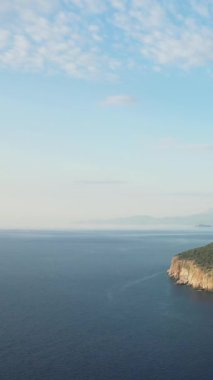Yunanistan 'ın Mani Yarımadası' ndaki Diros Sahili yakınlarında yakalanan berrak mavi suyu ve parçalı bulutlu gökyüzü ile kayalık bir kıyı şeridi manzarası.