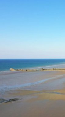 Fransa 'nın Asnelles kentindeki Gold Beach manzarası sakin mavi deniz, kumlu sahil ve açık gökyüzü..